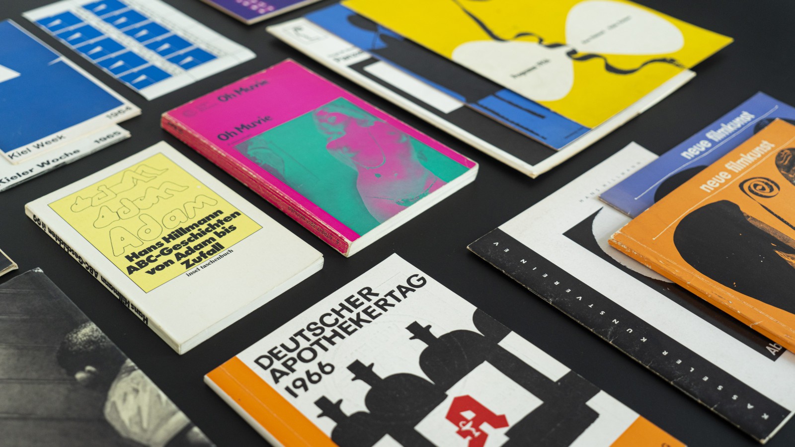 Draufsicht auf mehrere Hans-Hillmann-Druckerzeugnisse: Filmplakate, Buchumschläge und Programmhefte