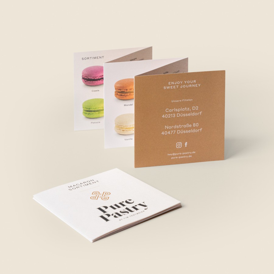 Pure Pastry flyer mockup on a beige background: unfolded product catalog featuring a macaron illustration, with a brown reverse side displaying contact information