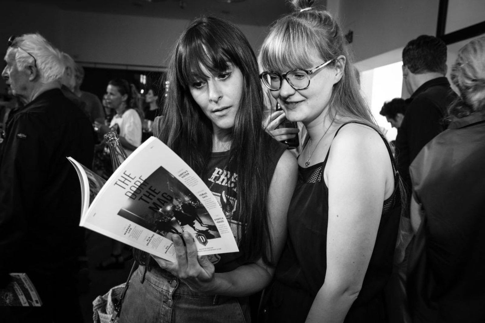 Black-and-white photo of two women at THE DORF THE MAG Release Party No. 1, one of whom is holding a copy of the magazine