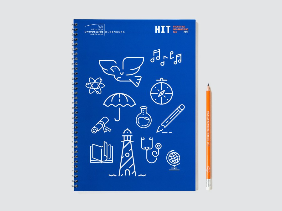 Blue HIT notebook with spiral binding and white line-art icons: bird's wing, globe, magnifying glass, book, lighthouse, and globe, with an orange pencil next to them